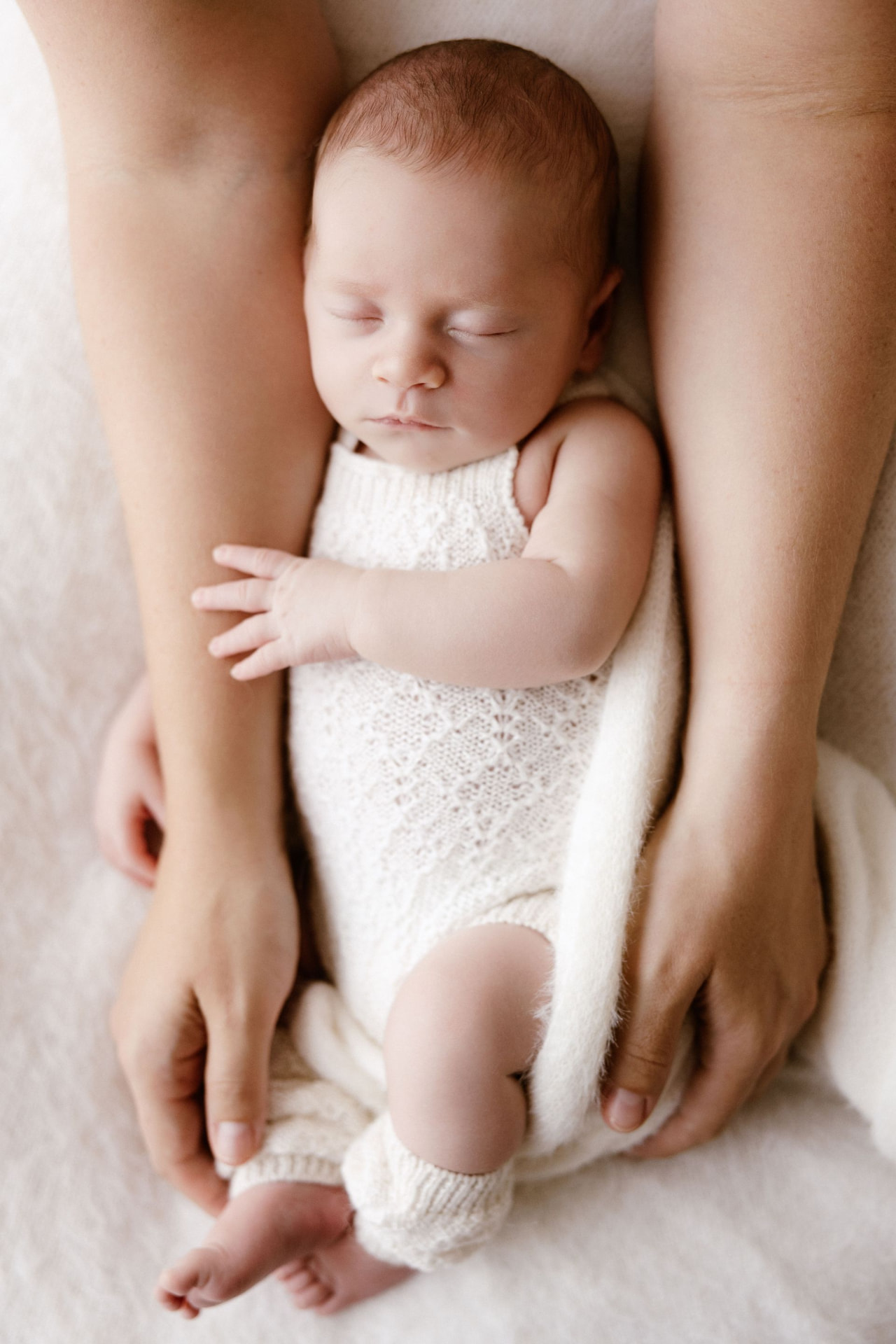 Newborn resting safely between mum's hands