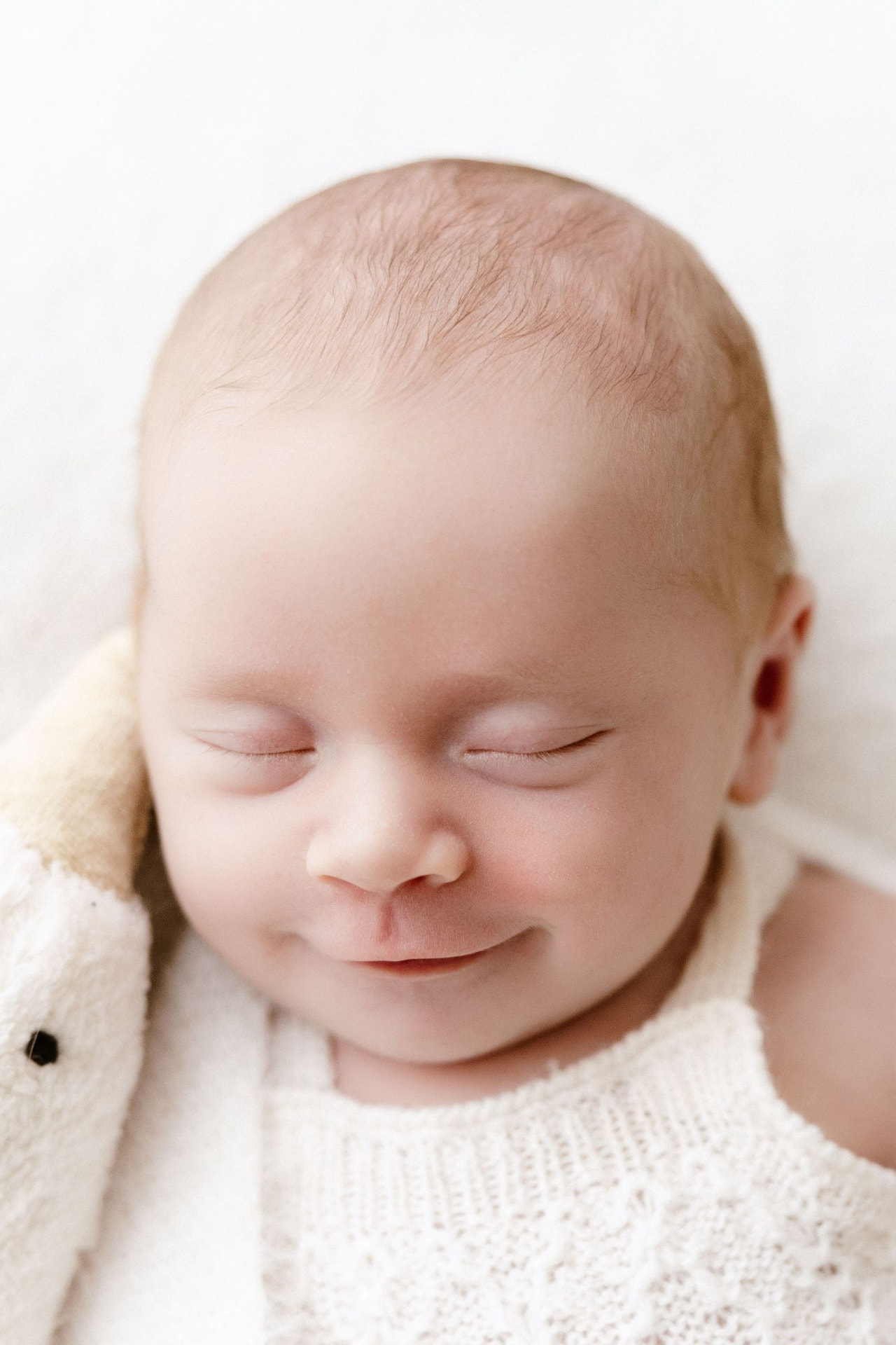 Close up of a newborn smiling in her sleep