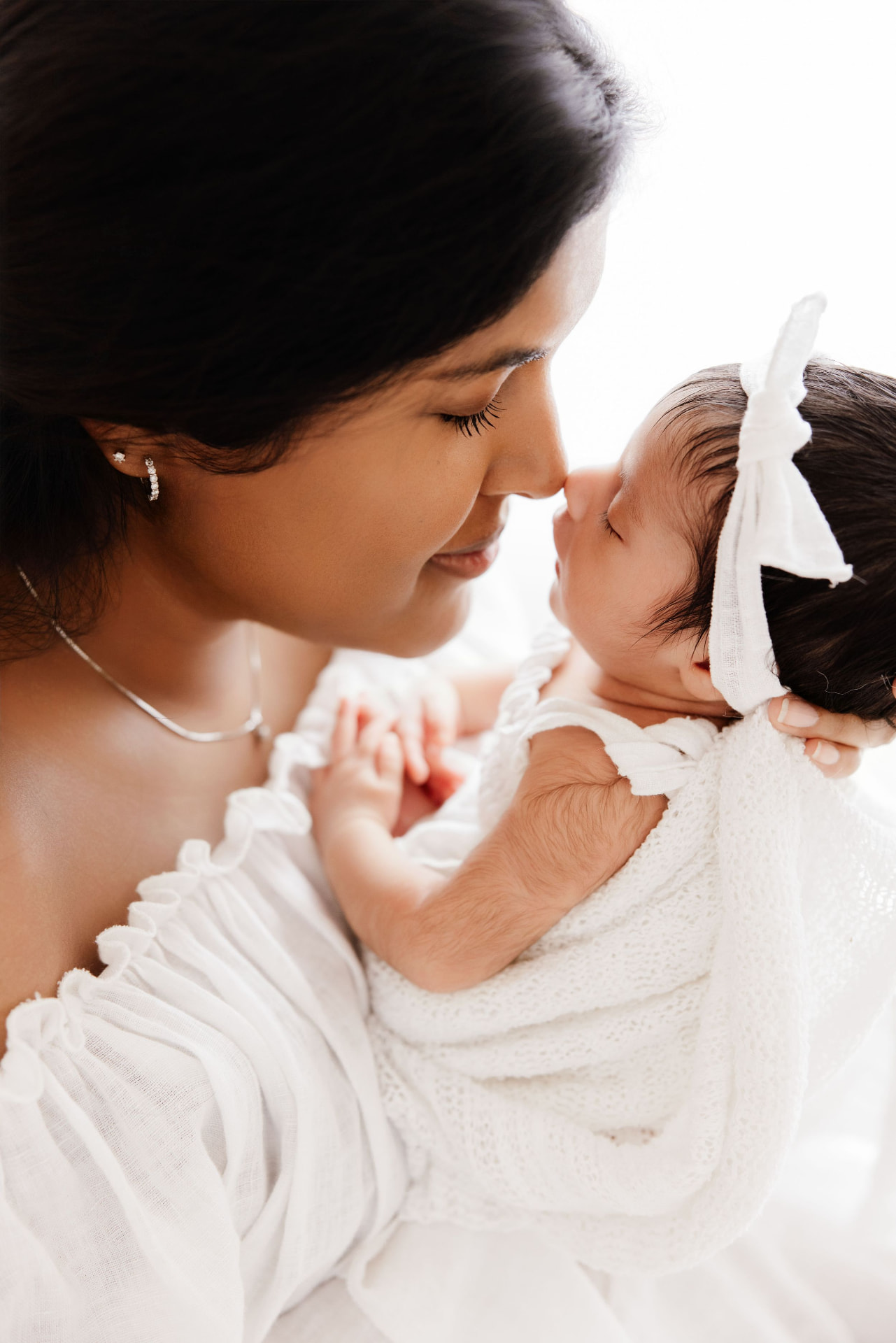 Mum touching noses with her newborn daughter