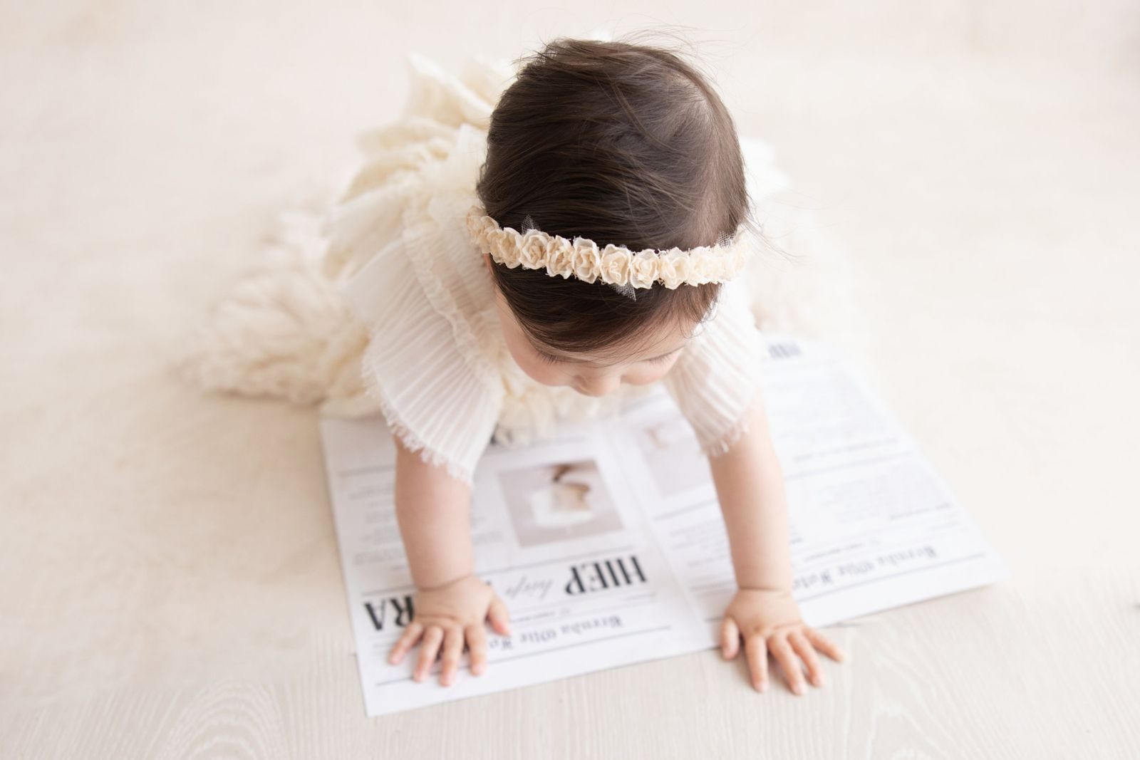 Baby crawling over a first birthday newspaper