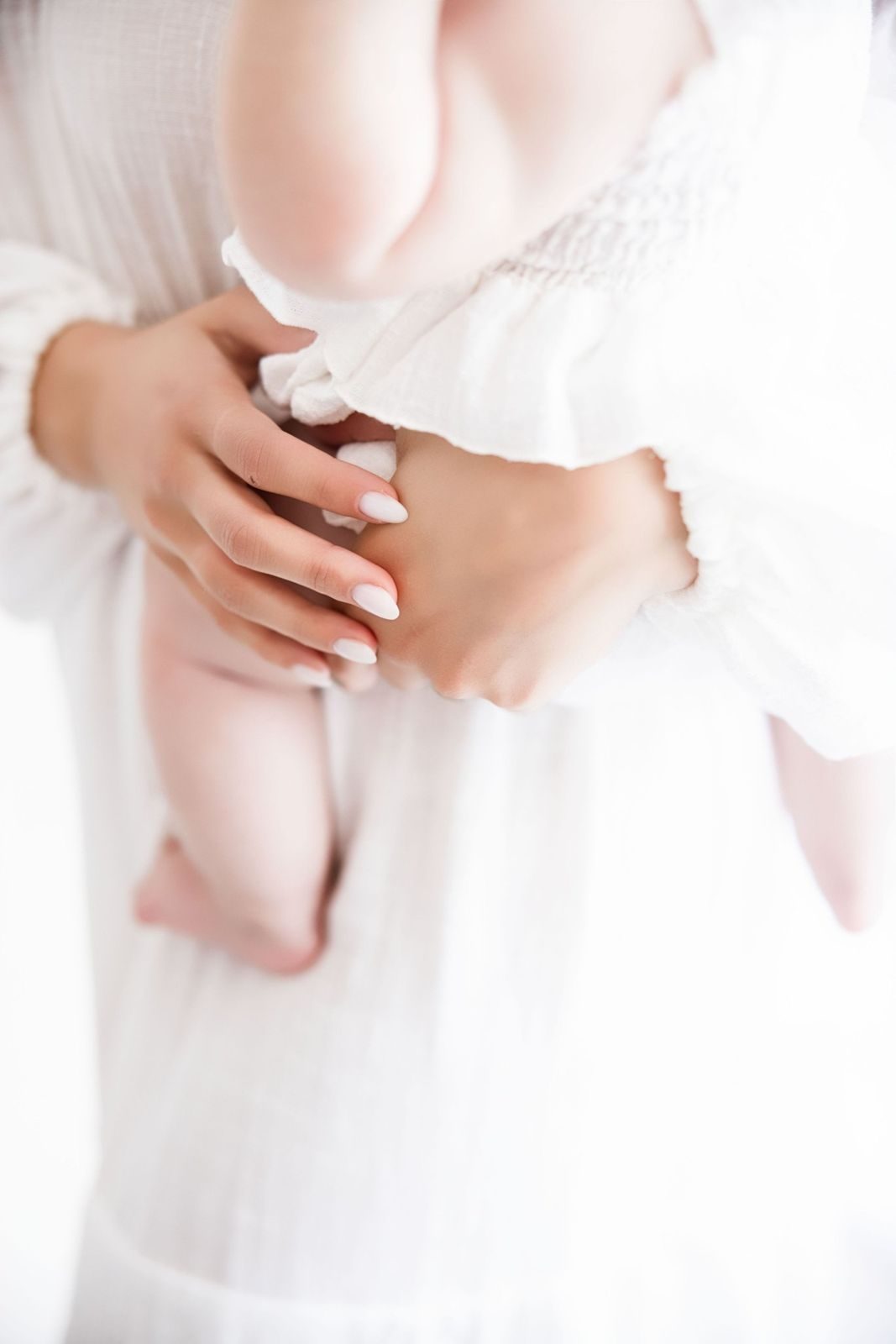 Mother's hand holding her baby's chubby legs