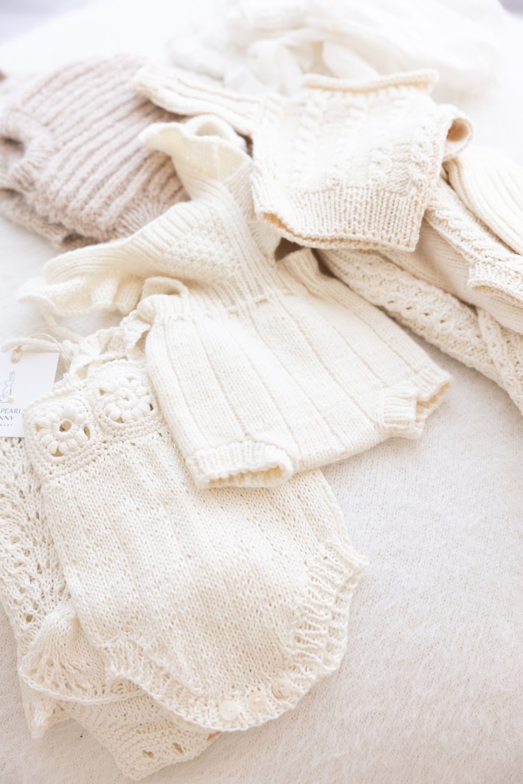 Cream knitted baby outfits laid out