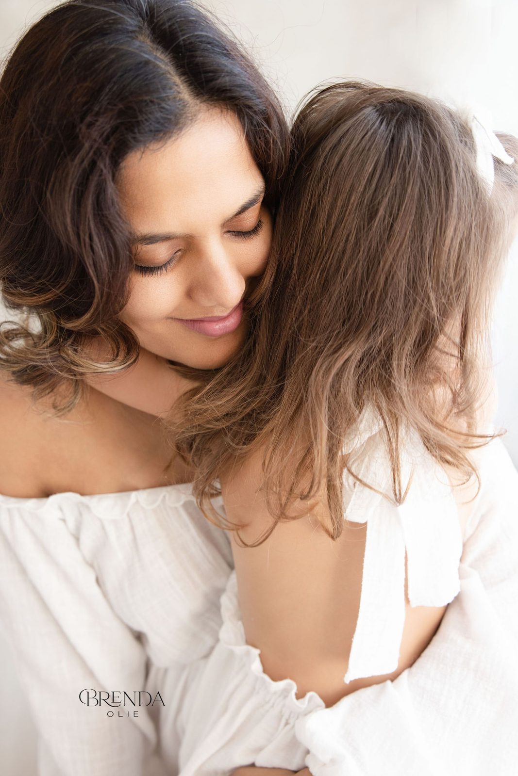 Expecting mother holding her daughter close against her shoulder