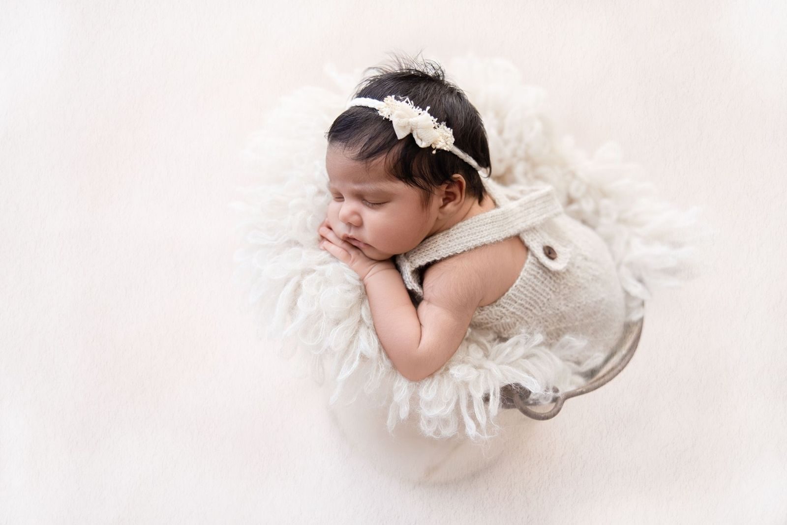Newborn posed asleep in a bucket on soft wool