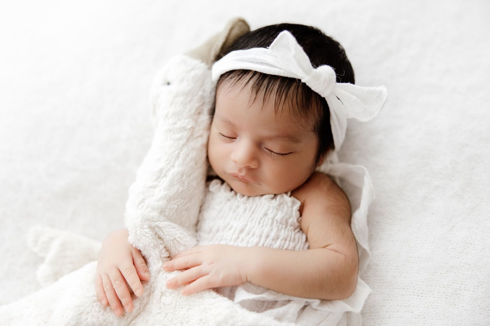 Close up of a sleeping newborn with a white bow