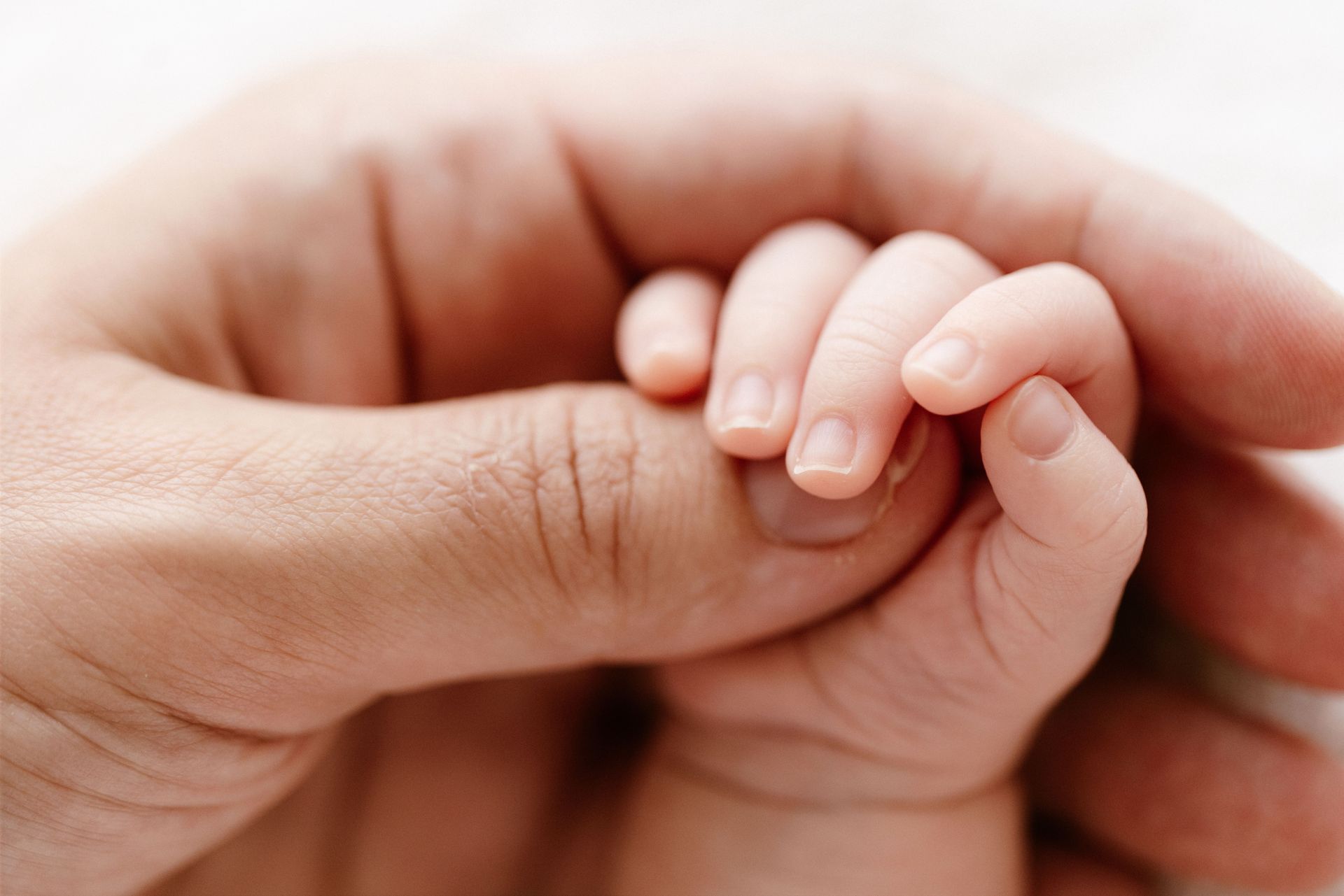 Baby fingers curled around her father's finger