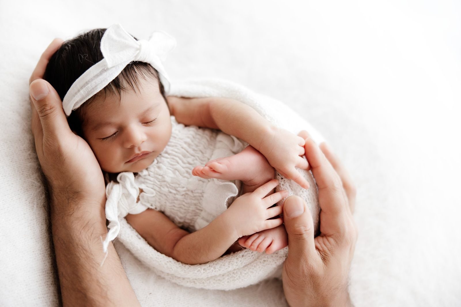 Newborn cradled in her parents' hands