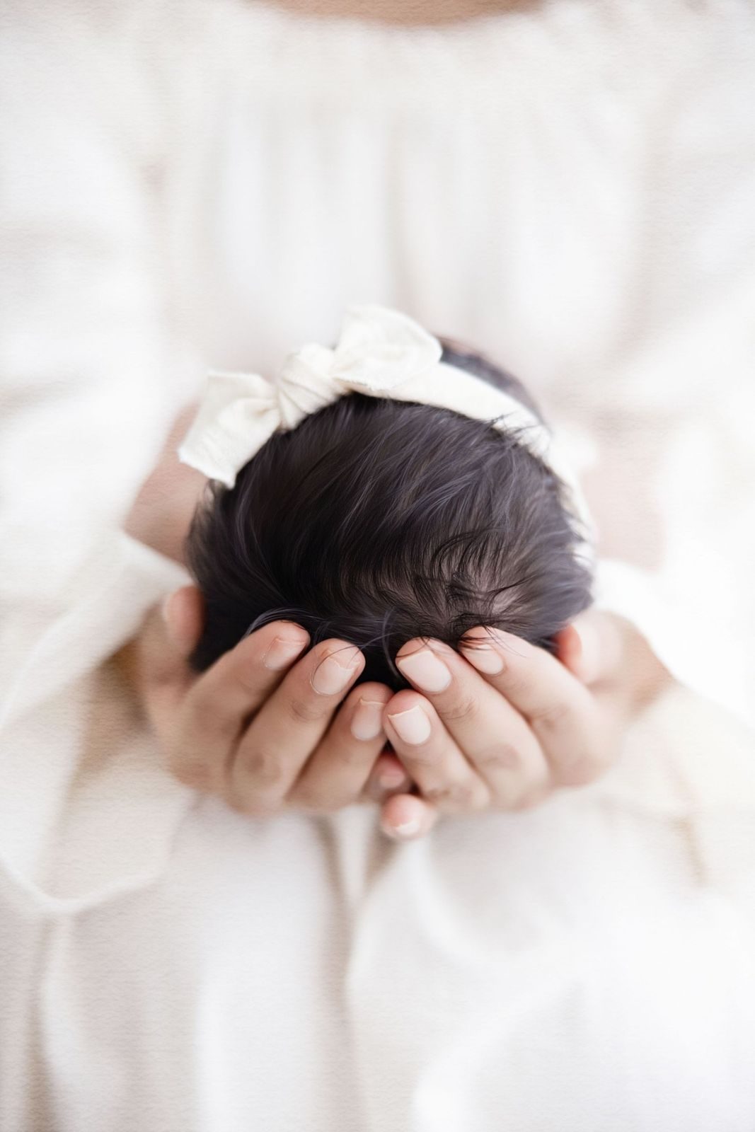 Mother's hands cradling her newborn's head