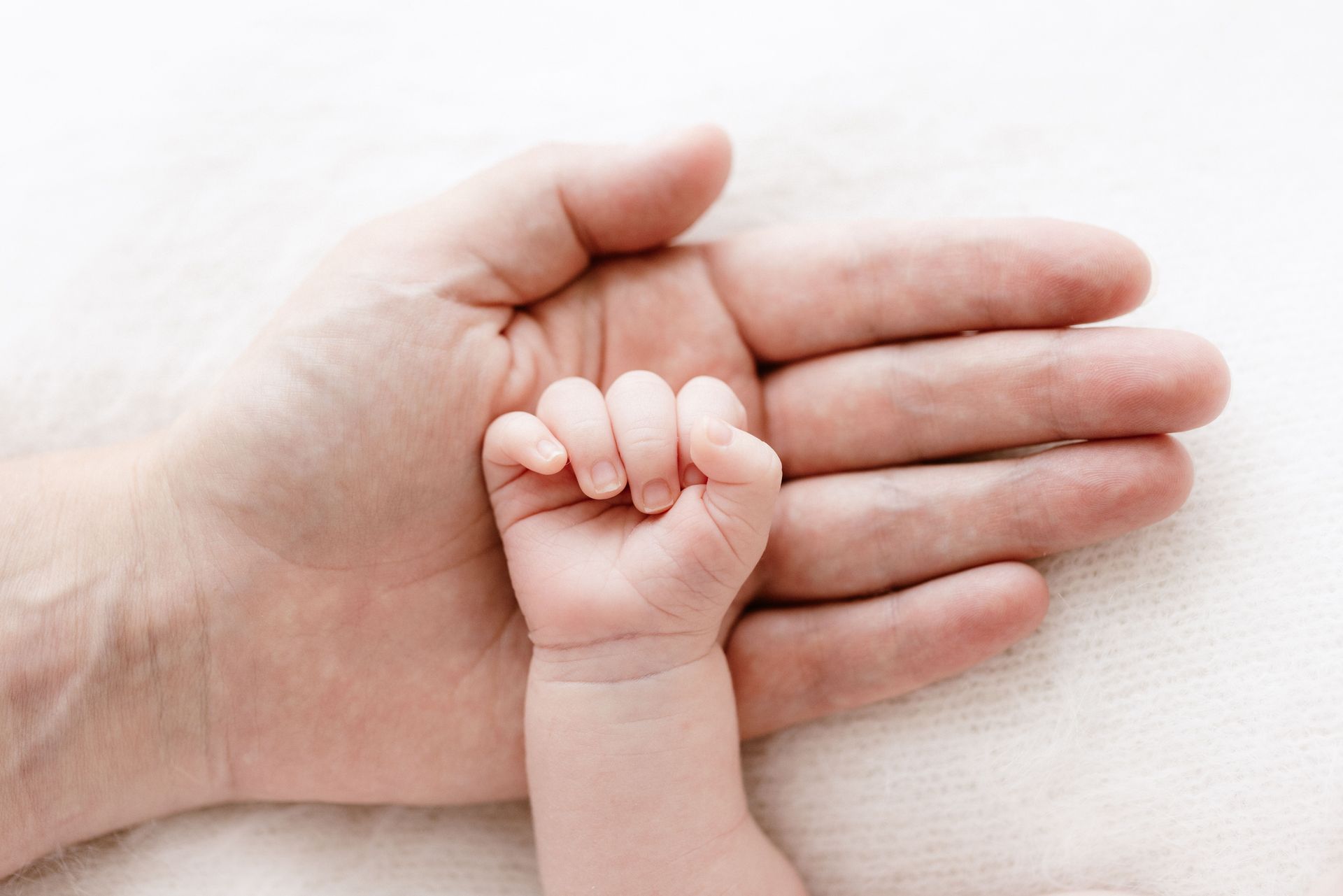 Baby hand resting in her father's palm