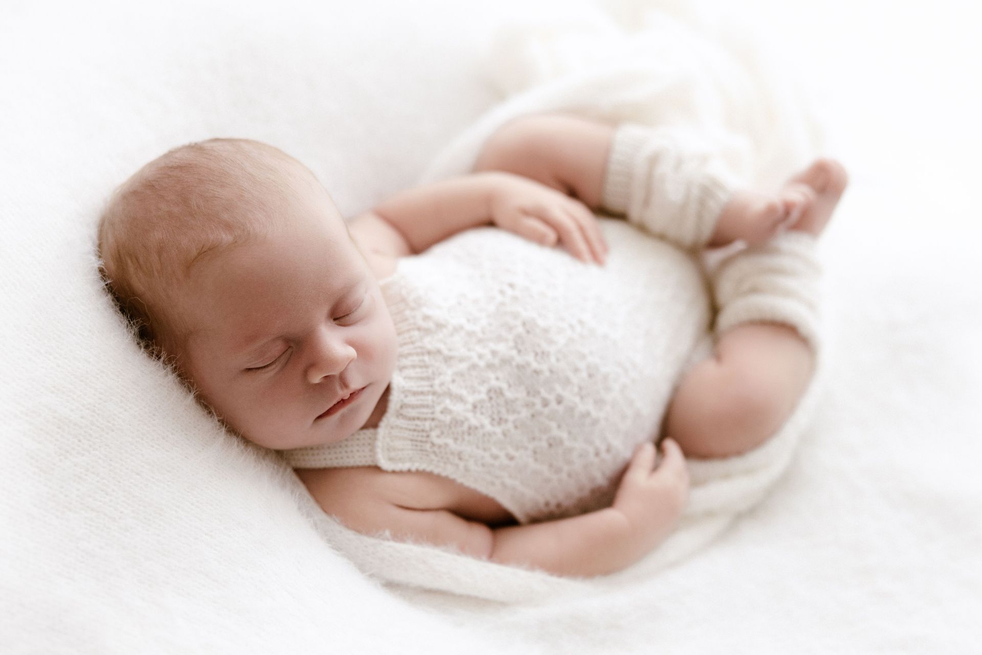 Sleeping newborn in a soft knitted romper