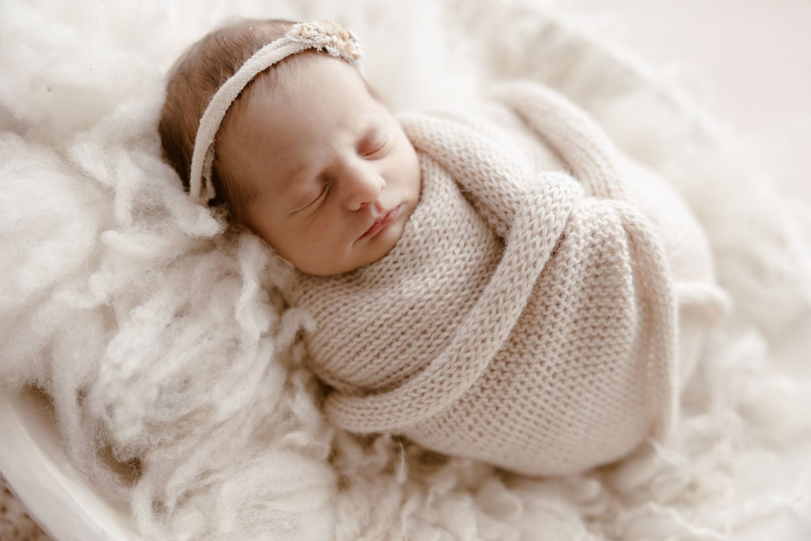 Wrapped newborn sleeping on soft wool