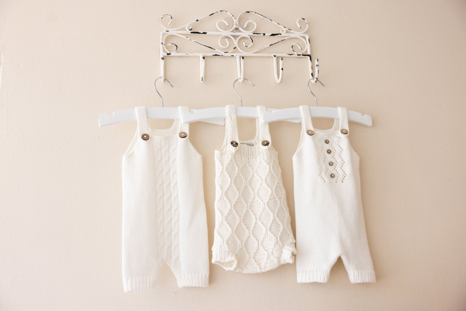 Three knitted rompers on a vintage wall hook
